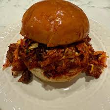 Heirloom Market BBQ signature dishes Spicy Korean Pork Sandwich, 12-Hour Smoked Brisket, Kimchi Slaw, Gochujang-marinated Ribs